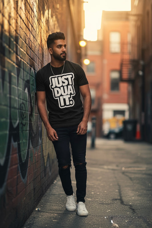 Man wearing a black t-shirt with 'JUST DUA IT' text standing against a graffiti-covered wall.