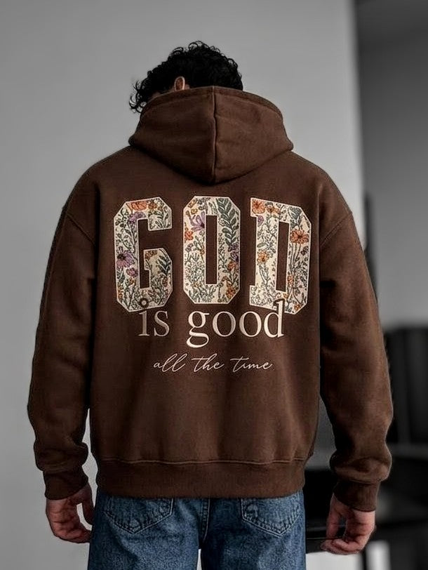 Man wearing a chocolate brown hoodie with HV floral logo on chest and back view showing God is Good floral varsity text.