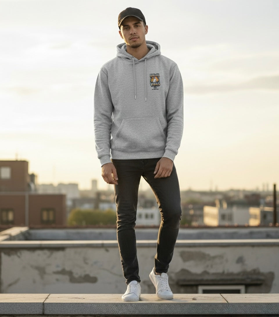 Person wearing a gray hoodie with Halal Vibes  logo on a rooftop during sunset.