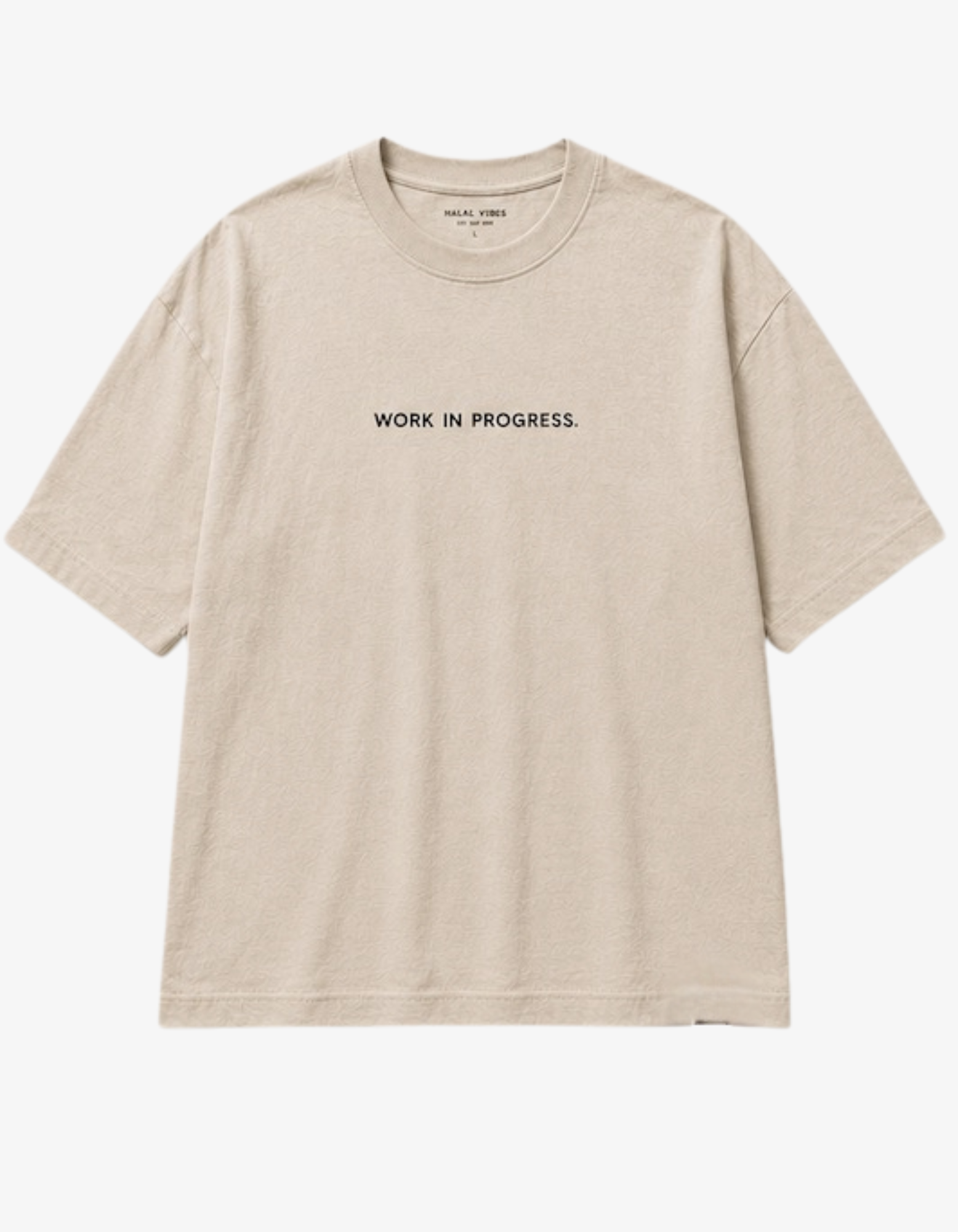 A light beige crewneck t-shirt with 'WORK IN PROGRESS.' printed in black capital letters across the chest, displayed flat against a light gray background.