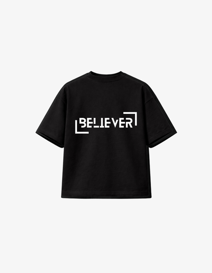 Front view of black oversized t-shirt with white BELIEVER architectural typography design.