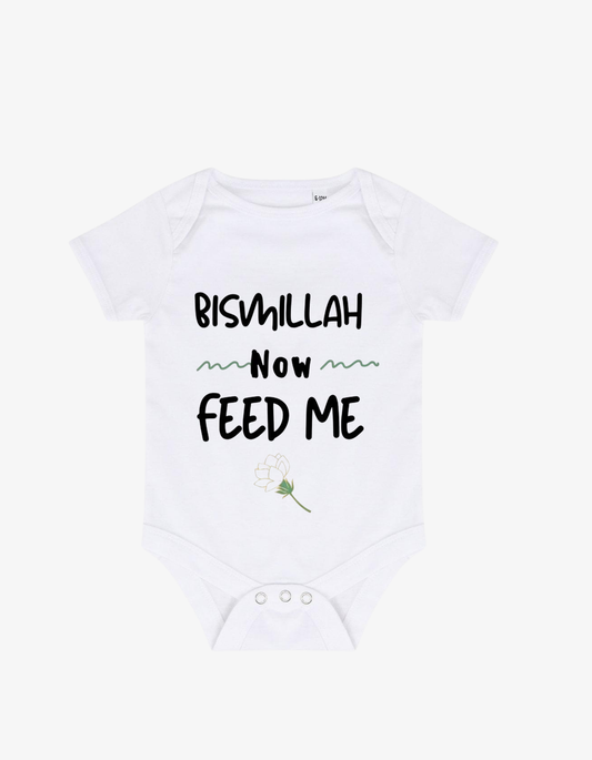 White baby grow with black typography saying Bismillah Now FEED ME and a small white rose illustration.