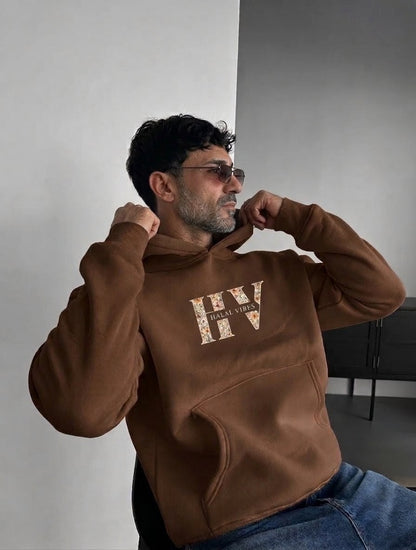 Man wearing a chocolate brown hoodie with HV floral logo on chest and back view showing God is Good floral varsity text.