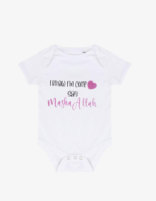 White baby grow with pink glitter heart and text saying I know I'm cute say Masha'Allah.