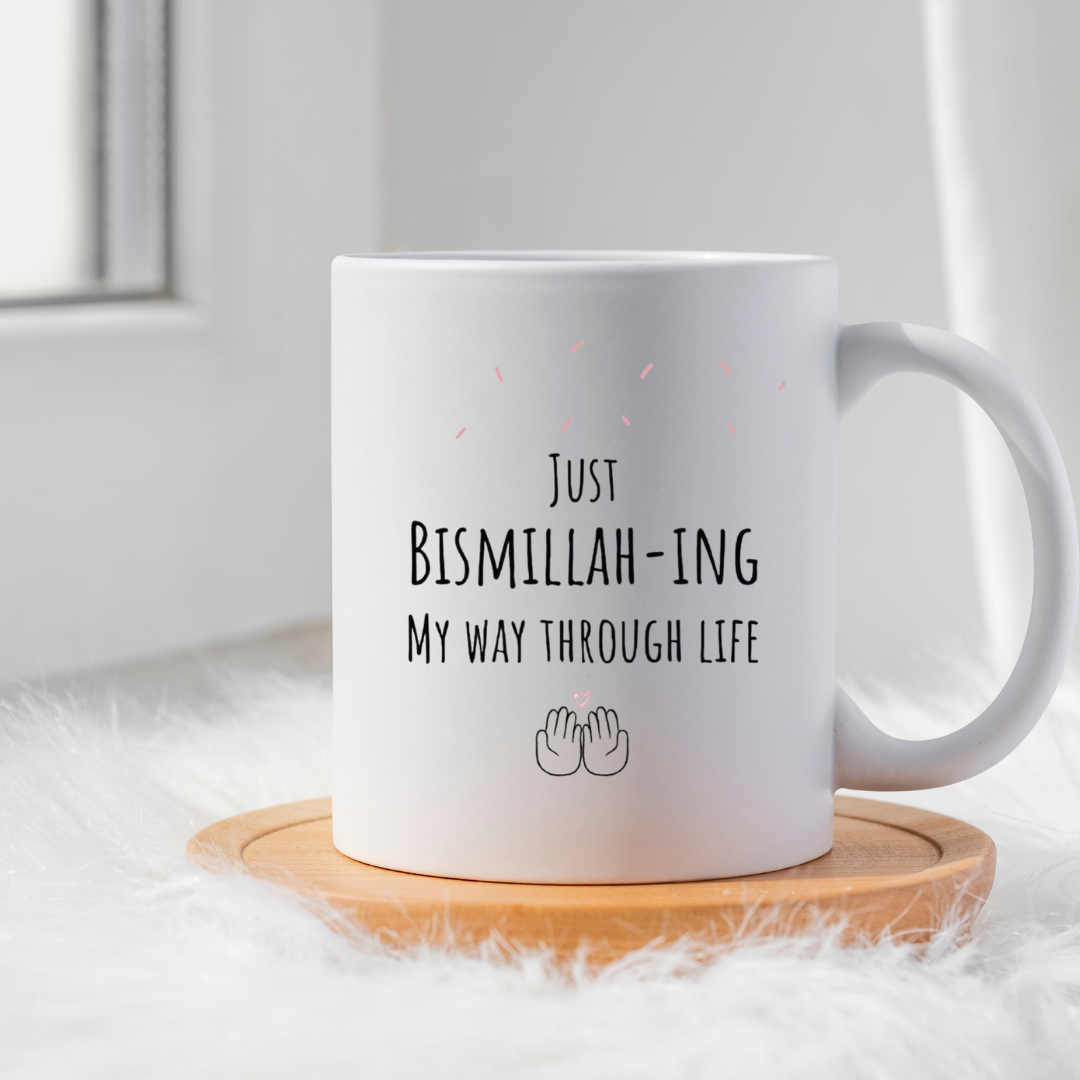 White ceramic mug featuring the text Just Bismillah-ing My Way Through Life on a wooden coaster.