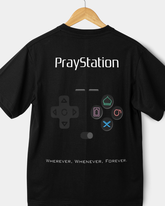 Rear view of a black 180gsm regular fit t-shirt with "PrayStation" text and a gaming controller graphic featuring masjid and Quran icons.