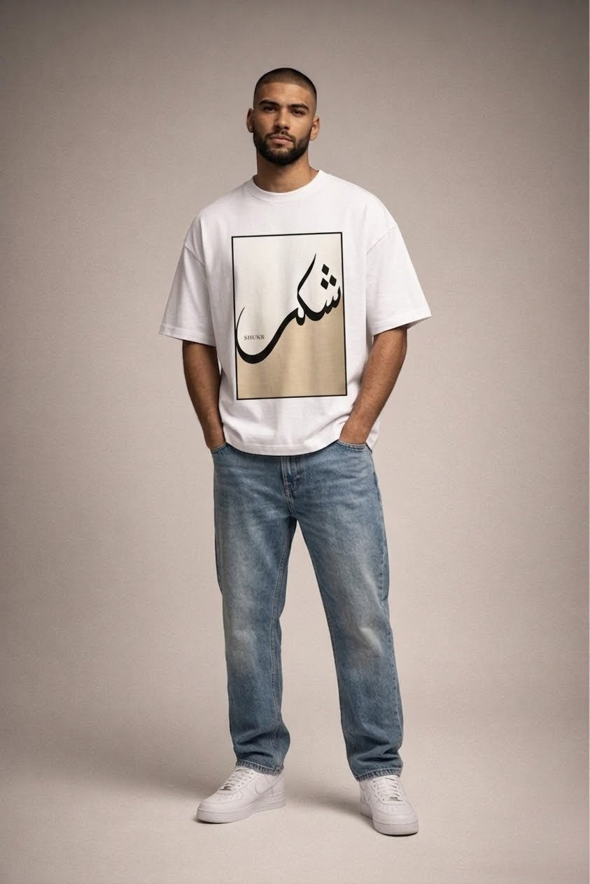Man wearing a white t-shirt with Arabic text and blue jeans on a beige background